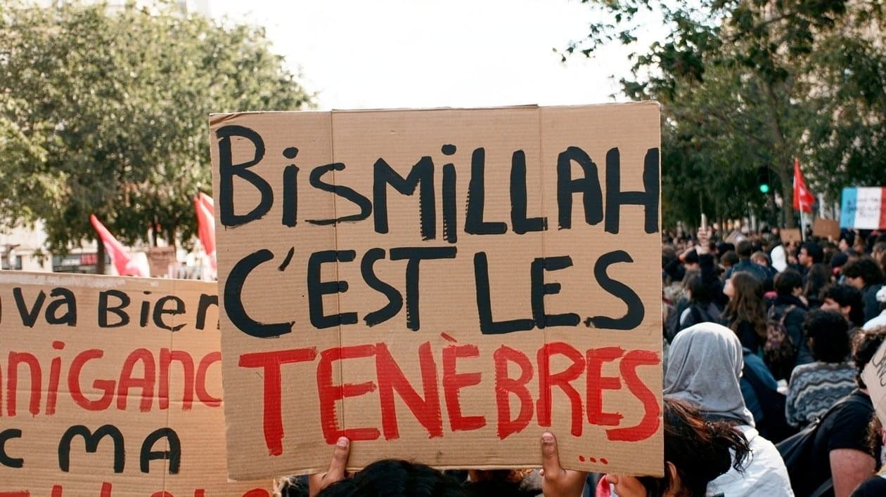 Fransa’da gençler, kendilerini taklit etmeye çalışan şüpheli hesapların dilini protesto sloganına çevirdi. “Bismillah, c’est les ténèbres” pankartlarda yayılırken, mizahın hedefinde gençlere yönelik kalıp yargılar ve polis gözetimi var.